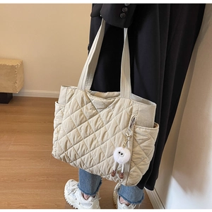 Detail of beige quilted nylon tote bag with side pocket and plush charm accessory
