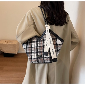 Detail of checkered tote bag featuring a V-shaped cut and stylish letter ribbon