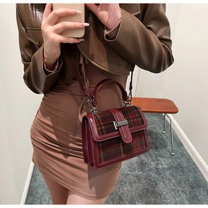 Detail of vintage plaid handbag with burgundy leather trim and metal clasp closure