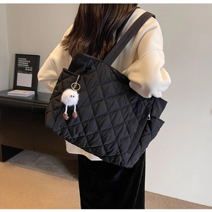 Close-up of black quilted nylon tote bag with creative white plush monster charm