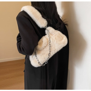 Détail de la texture en fausse fourrure sur un sac crème avec bandoulière chaîne en métal