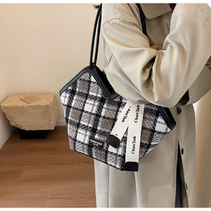 Close-up of a large plaid tote bag in grey tweed fabric worn on a shoulder