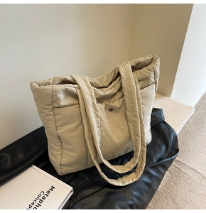 Detail view of cream quilted puffer tote bag with magnetic metal snap button closure