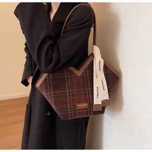 Detail of large vintage plaid tote bag with brown leather straps and fashion label tag