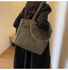 Detail of olive green quilted nylon puffer tote showing side pocket and metal button