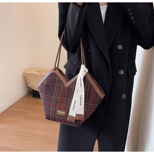 Detailed view of large tote bag with red and green plaid fabric and brown leather straps