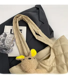 Detail of beige quilted nylon tote bag with plush bunny charm and wide shoulder strap
