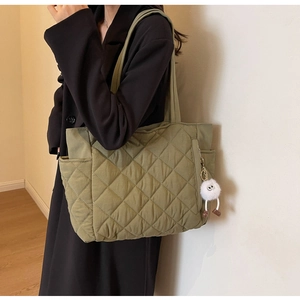 Olive green quilted nylon tote bag with side pocket and fluffy monster charm detail