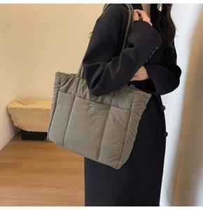 Detailed view of olive green quilted nylon tote bag with magnetic snap and wide strap