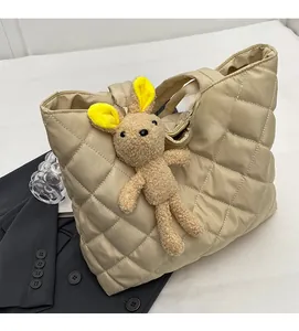 Detail of light beige quilted nylon tote bag featuring a brown plush bear charm and菱格 pattern