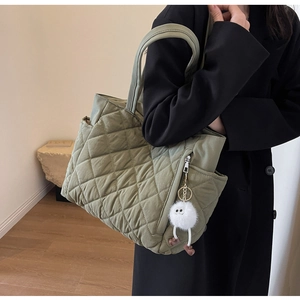 Detail of khaki quilted nylon tote bag with side zipper pocket and plush toy charm