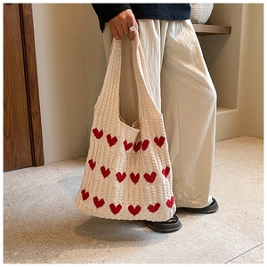 Gros plan du sac cabas en tricot crème avec motifs de cœurs rouges et texture rayée