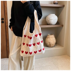 Détail du motif de cœur et de la texture tressée douce sur ce sac cabas en tricot