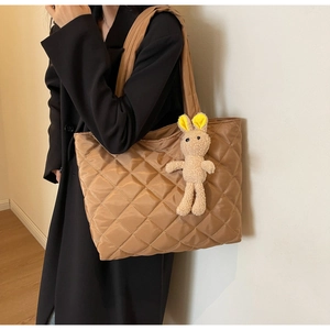 Quilted nylon tote bag in khaki with a cute plush rabbit pendant shown on a model