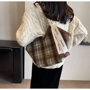 Detail of vintage plaid tote bag featuring brown piping and branded woven shoulder strap