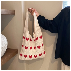Gros plan du sac cabas en tricot beige avec motifs de cœurs rouges et maille torsadée