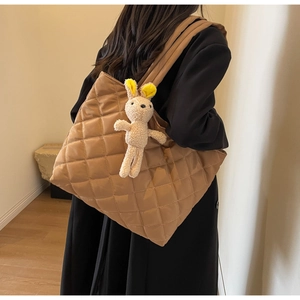 Detail of camel quilted tote bag featuring a cute plush bunny charm and wide shoulder strap