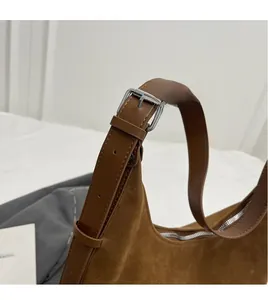 Detail of adjustable leather strap and silver metal buckle on brown suede bucket bag