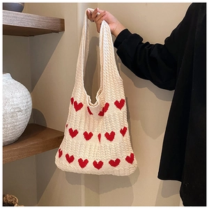 Détail du sac cabas en tricot crème avec cœurs rouges et texture de maille