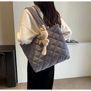 Detail of grey quilted nylon tote bag with plush rabbit charm and wide shoulder strap