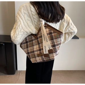 Close-up of brown checkered wool tote bag with leather trim and decorative strap detail