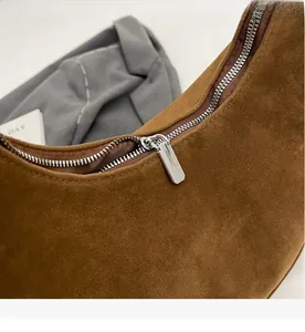 Close-up of smooth silver metal zipper on premium brown suede leather dumpling bag