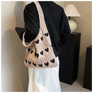 Détail du sac cabas en tricot avec motifs de cœurs noirs et texture tissée souple