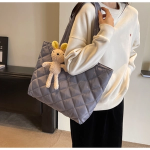 Detail of navy quilted nylon tote bag with plush bunny charm accessory on the strap