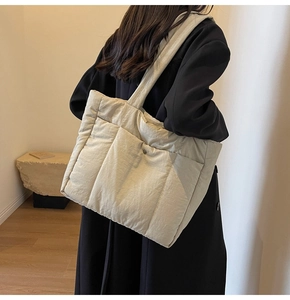 Detail of off-white quilted tote bag with large front pockets and metallic snap buttons