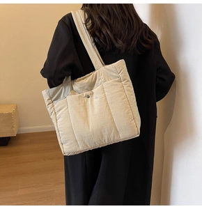 Rear view of a model wearing the beige quilted nylon tote bag with large front pocket