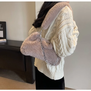 Détail d'un sac bandoulière en fausse fourrure rose avec chaîne argentée sur un pull
