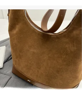 Detail of dark brown suede and smooth leather texture on a crescent shoulder bag