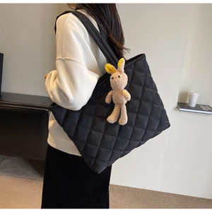 Detail of black quilted nylon tote bag with cute plush rabbit charm and shoulder strap