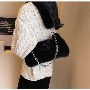 Détail d'un sac bandoulière en fausse fourrure noire avec chaîne et boucle cœur