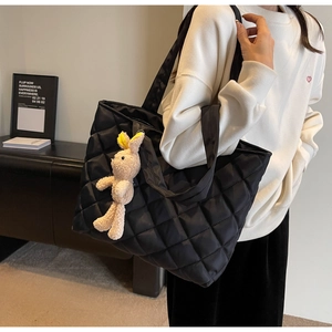 Close-up of black quilted nylon tote bag with a cute plush rabbit charm on shoulder