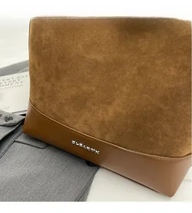 Close-up of brown suede and leather tote bag featuring a silver metal logo detail