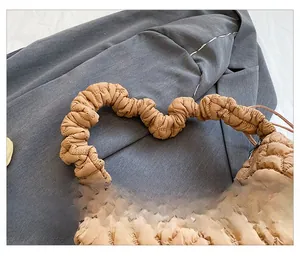 Detail of light brown quilted nylon bag featuring a soft pleated cloud handle design