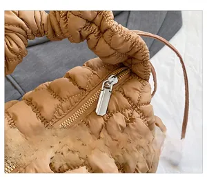 Detail of silver zipper and quilted nylon fabric texture on caramel hobo bag