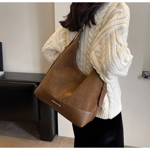 Detailed texture of brown suede hobo bag with smooth leather trim and metal logo