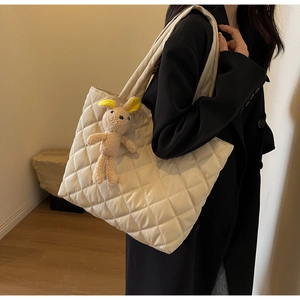 Detail of beige quilted nylon tote bag featuring a cute plush bunny charm on shoulder strap