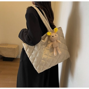 Detail of beige quilted nylon tote bag with cute bunny charm on shoulder strap