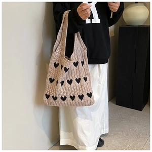 Vue détaillée de la texture tricotée à motif de cœur d'un grand sac beige