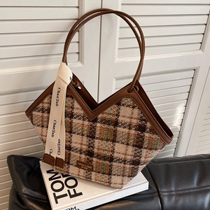 Retro plaid tote bag with V-shaped opening and brown leather trim on a modern sofa
