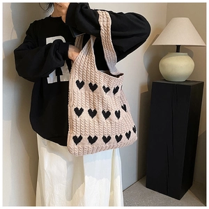 Détail du sac cabas en tricot souple avec motifs cœurs noirs et texture épaisse
