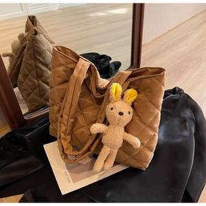 Detail of brown quilted nylon tote bag with a cute plush rabbit charm and mirror reflection