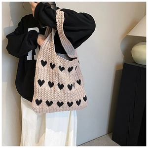 Gros plan du sac cabas en tricot rose avec motifs de cœurs noirs et tissu doux