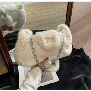 Détail d'un sac en peluche blanc avec chaîne argentée et étiquette en cuir siglée