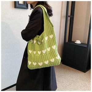 Détail d'un sac cabas en tricot vert avec motifs de cœurs blancs et texture en coton