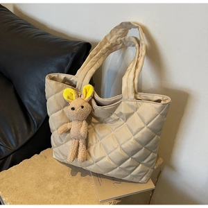 Detail of beige quilted nylon tote bag with rhombus pattern and cute rabbit charm