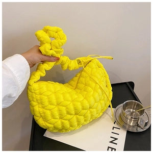 Detail of a bright yellow quilted nylon dumpling bag with a unique knot design on the handle